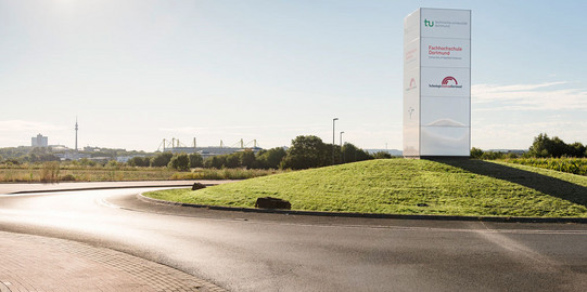 Roundabout with a sign including the logos of TU Dortmund University and the University of Applied Sciences of Dortmund